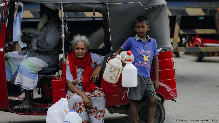 An old woman and a boy with empty fuel containers.