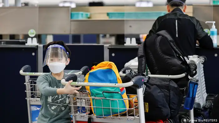 Ein Junge sitzt in einem Gepäckwagen am internationalen Flughafen Hongkong