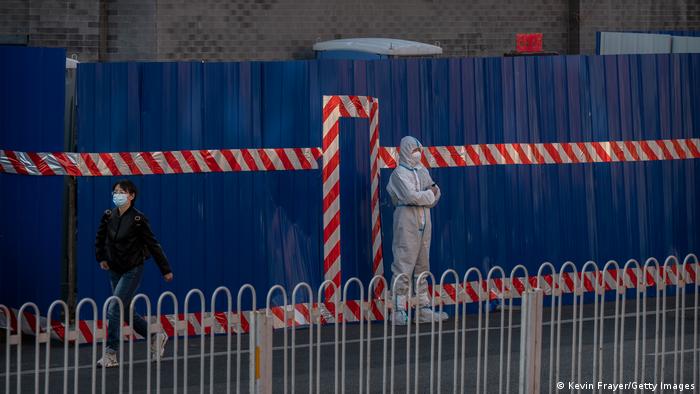 Ein Wachmann in Schutzkleidung vor dem Eingang eines abgeriegelten Stadtbezirks in Peking