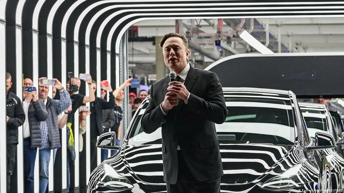 Empresário Elon Musk fala ao microfone, cercado por espectadores