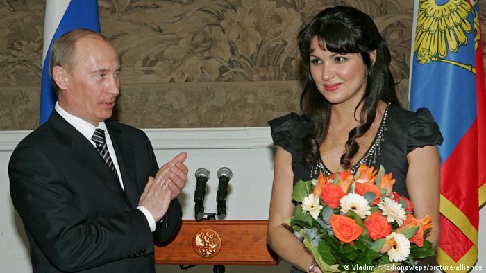 Vladimir Putin sits beside Anna Netrebko and applauds
