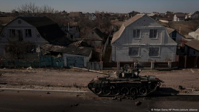 A destroyed Russian tank near Kyiv, damaged houses in the background
