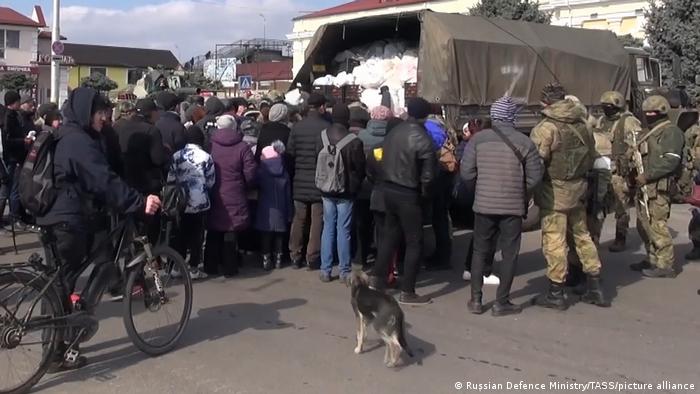 Kherson civilians gather around a military truck delivering aid