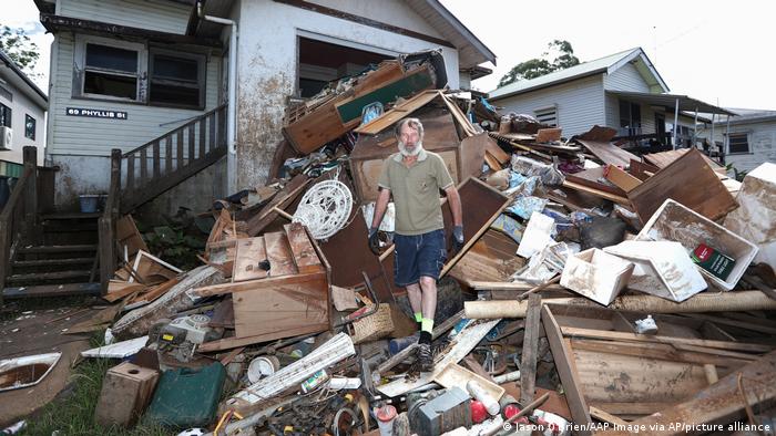 Resident Ken Bridge stands on a pile of his flood-damaged furniture outside his home in Lismore, Australia, Wednesday, March 9, 2022.