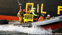 23.03.2022 Aktivisten der Umweltorganisation Greenpeace malen den Schriftzug «Oil fuels war» auf den Rumpf eines Schiffes, das russisches Öl auf der Ostsee transportiert. Eine Frau hält ein Schild mit der Aufschrift Kein geld für Krieg.