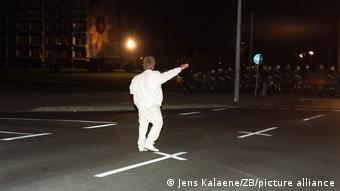 Eein Mann geht über die Straße und zeigt den Hitlergruß, von hinten fotografiert.