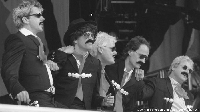 Black-and-white photo of men wearing sunglasses, mustaches and suits.
