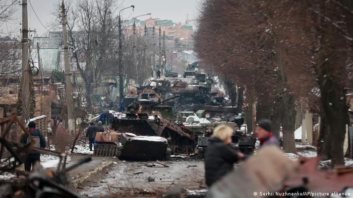 Un grupo de personas observa los restos destruidos de vehículos militares rusos en una carretera de la ciudad de Bucha, cerca de la capital, Kiev.