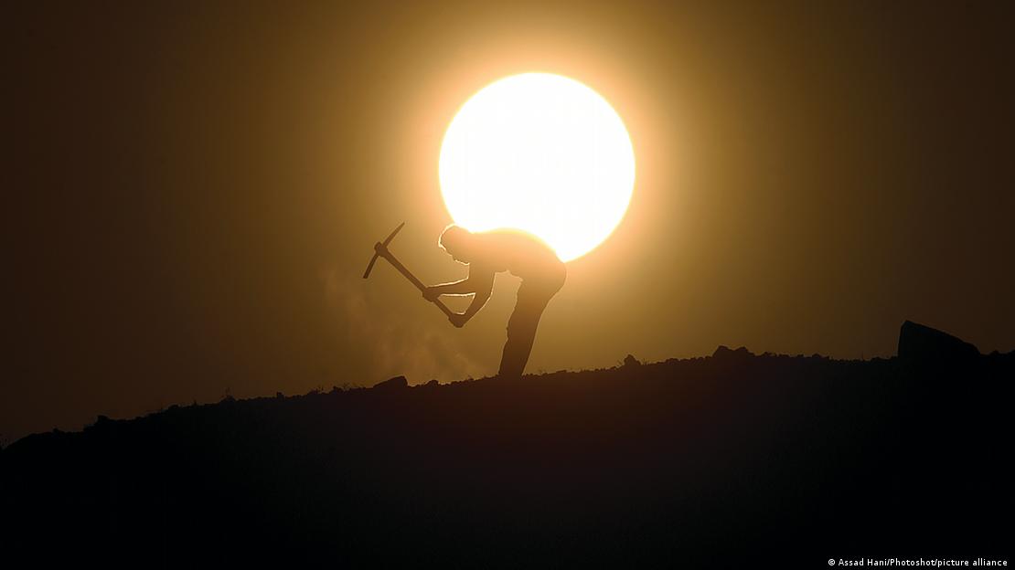 Silhueta de homem trabalhando na terra com uma picareta. Ao fundo, brilha a sol. Silhueta de homem trabalhando na terra com uma picareta. Ao fundo, brilha a sol.