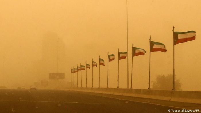 A row of Kuwaiti national flags are pictured along a highway during a heavy sand storm in the capital Kuwait City