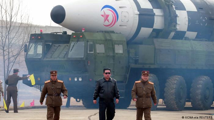 Kim Jong Un wears sunglasses near a large missile