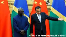 FILE - Solomon Islands Prime Minister Manasseh Sogavare, left, and Chinese Premier Li Keqiang attend a signing ceremony at the Great Hall of the People in Beijing, Wednesday, Oct. 9, 2019. The Solomon Islands' decision to switch its diplomatic allegiance from Taiwan to Beijing in 2019, has been blamed for arson and looting in the capital Honiara, where protesters are demanding the prime minister's resignation. (Thomas Peter/Pool Photo via AP, File)