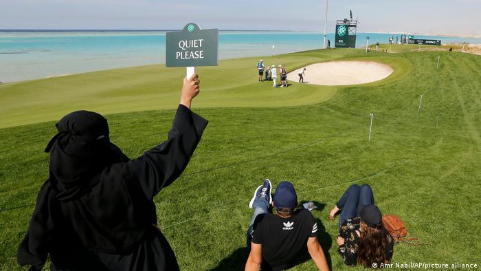 Bei der Saudi Golf Championship hält eine verschleierte Frau am Rande des Golfkurses ein Schild mit der Aufschrift Quiet please