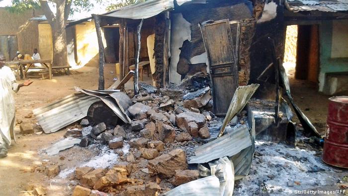 A resident inspects a burnt house after a group of bandits attacked his village 