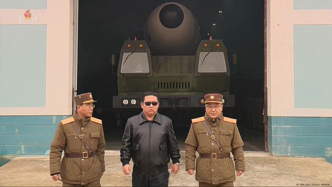 Kim Jong-un no meio de dois militares norte-coreanos em frente a um suposto míssil Hwasong-17