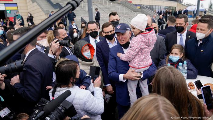 US-Präsident Biden inmitten von Menschen und mit einem Kind auf dem Arm trifft Ukraine-Flüchtlinge in Warschau