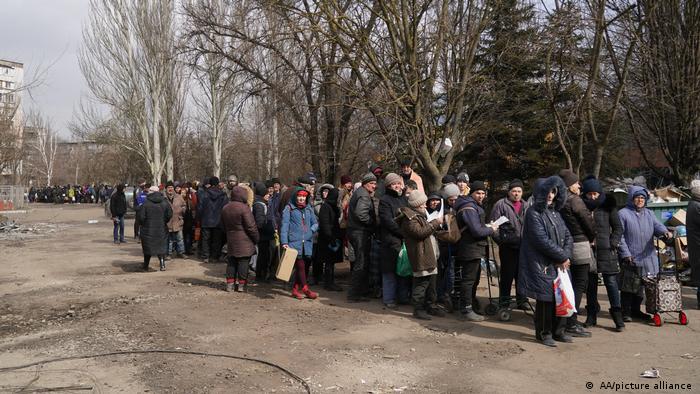 People wait in a group to be evacuated along humanitarian corridors from Mariupol