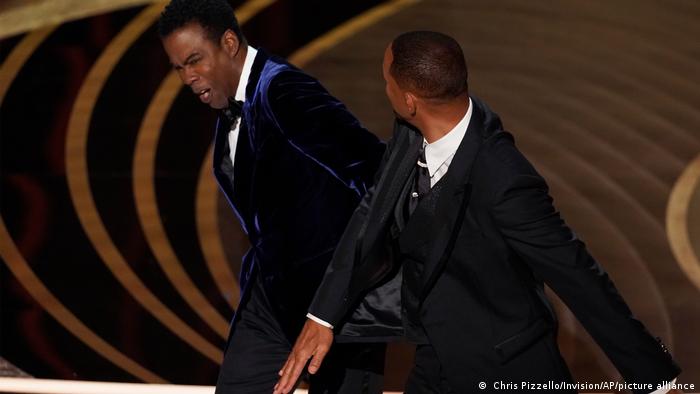 Will Smith, right, hits presenter Chris Rock on stage