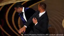 Will Smith, right, hits presenter Chris Rock on stage while presenting the award for best documentary feature at the Oscars on Sunday, March 27, 2022, at the Dolby Theatre in Los Angeles. (AP Photo/Chris Pizzello)