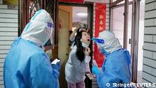 A worker in a protective suit collects a swab from a resident at a residential compound under lockdown, following the coronavirus disease (COVID-19) outbreak in Shenzhen, Guangdong province, China March 14, 2022. Picture taken March 14, 2022. cnsphoto via REUTERS ATTENTION EDITORS - THIS IMAGE WAS PROVIDED BY A THIRD PARTY. CHINA OUT. 