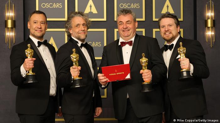 Cuatro hombres levantan sus estatuillas del Óscar.