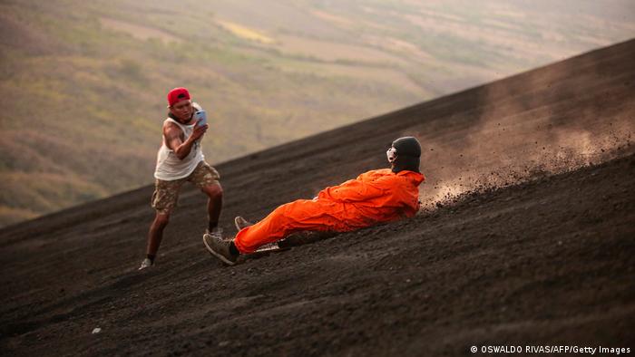 A tourist hurtles down Cerro Negro, as local guide Lester Centeno snaps a picture.