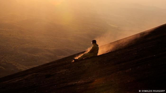 A tourist glides down the volcano in the twilight