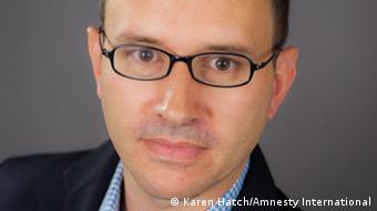  Philip Luther, of Amnesty International, wears glasses and a blue-checked collared shirt 