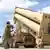 Sistema de mísseis Patriot sendo içado de veículo de transporte e erguido mecanicamente