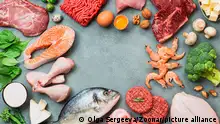 Keto diet concept. Raw ingredients for low carb diet - meat, poultry, fish, seafood, eggs, beef bones for bone broth, greens on gray stone background. Top view or flat lay. Copy space in center