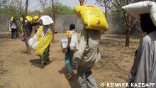 Cameroonian internally displaced carry food supplies at a camp in Kolofata, in the extreme north of Cameroon, during a food distribution provided by the International Red Cross Committee (ICR) on February 22, 2017. - The humanitarian crisis has strained Cameroon's government and aid agencies, and Boko Haram attacks have also driven people from Cameroon villages along the border. On February 22, 2017, the Red Cross distributed food to 2,500 displaced households at a camp in Kolofata. (Photo by Reinnier KAZE / AFP)