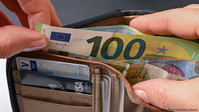 Hand taking a €100 note from a wallet