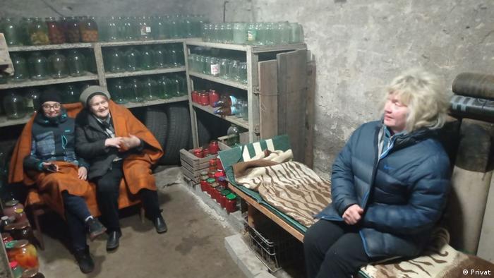 Three women in a basement with several glass bottles and jars
