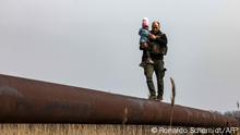 TOPSHOT - Ukrainian soldier Andriy carries the baby of a displaced family to help to cross a river, on the outskirts of Kyiv, on March 31, 2022. - Russian forces are repositioning in Ukraine to strengthen their offensive on the Donbass, Nato said March 31, 2022, on the 36th day of the Russian-Ukrainian conflict, as shelling continues in Kharkiv (north) and Mariupol (south). (Photo by RONALDO SCHEMIDT / AFP)