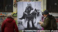 People pass by artwork representing Russia's President Vladimir Putin carrying his own dead body created by the Bulgarian artist Stanislav Belovski, applied on a wall in central Sofia, on day 36 of the Russian invasion in Ukraine, Thursday, March 31, 2022. (AP Photo/Valentina Petrova)