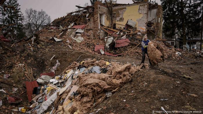 Man clearing debris from buildings destroyed during fighting