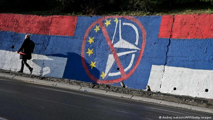 Eine Betonwand in serbischen Farben mit einem durchgestrichenen Symbol von EU und NATO