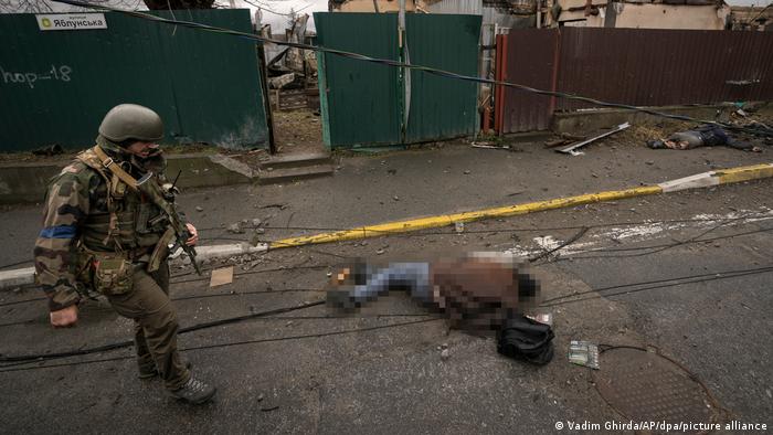 Un soldado ucraniano pasa junto a un cadáver que yace en una calle en el suburbio de Bucha (02.04.2022)