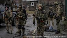 02.04.2022, Ukraine, Butscha: *** ATTENTION EDITORS GRAPHIC CONTENT *** Ukrainische Soldaten stehen im ehemals russisch besetzten Kiewer Vorort Butscha und untersuchen die Leichen von Zivilisten auf Sprengfallen. Der ukrainische Präsident Selenskyj warnte, dass die sich zurückziehenden russischen Truppen Minen, Ausrüstung und sogar die Leichen der Getöteten zurücklassen, wodurch eine katastrophale Situation für die Zivilbevölkerung entsteht. Foto: Vadim Ghirda/AP/dpa - ACHTUNG: Graphic Content +++ dpa-Bildfunk +++