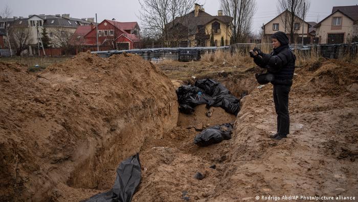 A journalist takes video of a mass grave in Bucha, on the outskirts of Kyiv