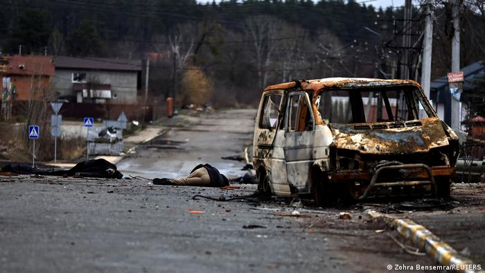 In the small town of Bucha, two dead bodies lie in the road in the middle distance next to a burnt-out van. Photo taken April 2, 2022.
