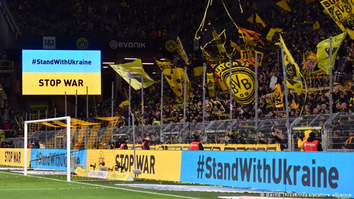 Stop War and #StandWithUkraine on dispaly screens around a Borussia Dortmund fans section