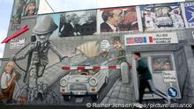 An Motiven der innerdeutschen Grenze entlang läuft ein Jogger am Montag (19.03.2007) an der so genannten East Side Gallery im Osten Berlins. Die Mauer in der Mühlenstraße in unmittelbarer Nähe zum Ostbahnhof ist einen Kilometer lang und es ist das längste erhaltene Stück Mauer in Berlin. Foto: Rainer Jensen dpa/lbn +++(c) dpa - Report+++