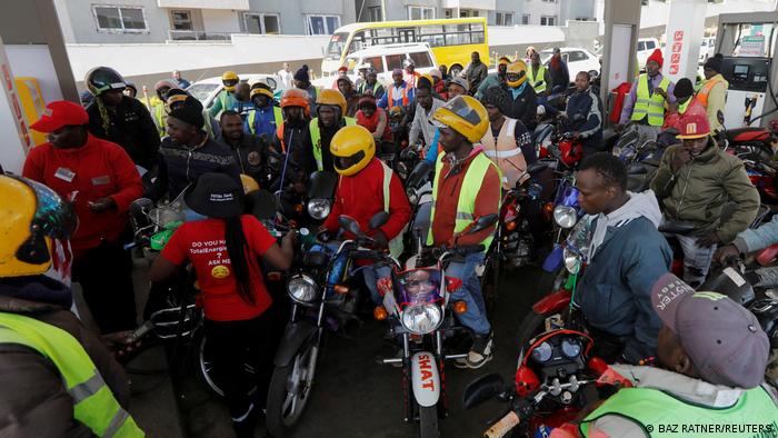Motorcycle taxi workers stand in line to fuel at a gas station in Nairobi