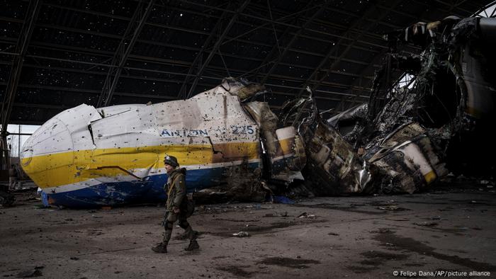 A Ukrainian serviceman walks past the burnt-out Antonov An-225 aircraft