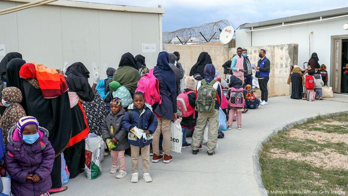 Des femmes et des enfants font la queue devant le bâtiment d'un aéroport en Libye.