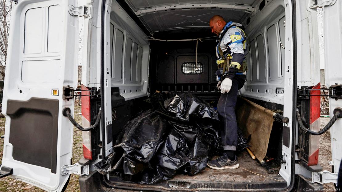 Homem em van, onde estão vários corpos enrolados em sacos pretos