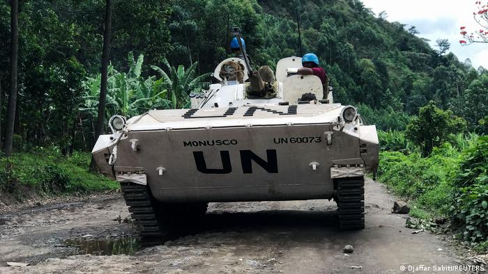 A UN tank drives down a dirt road