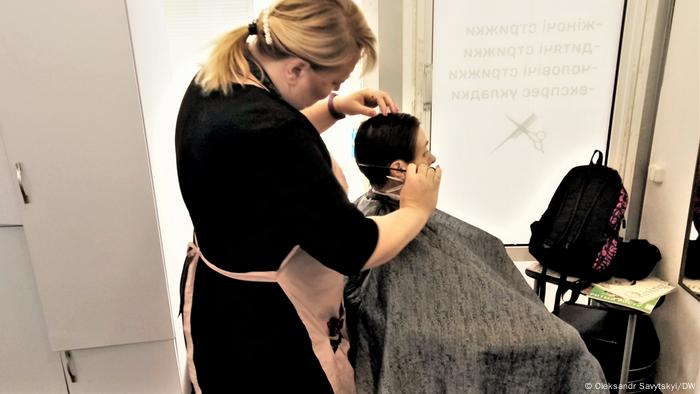 A woman cutting hair in a hairdressing salon