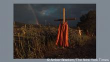 Rote Gewänder hängen an Kreuzen entlang einer Straße. Foto: Kamloops Residential School v. Amber Bracken